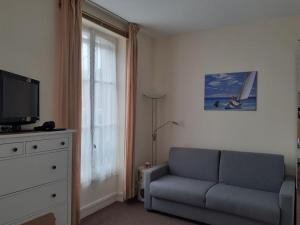 a living room with a couch and a television at Cabourg Charmant studio centre ville RUE DE LA MER in Cabourg