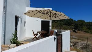 a patio with a table and an umbrella at Magic Nature Lodge in Marvão