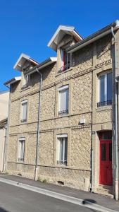 ein Backsteingebäude mit einer roten Tür auf einer Straße in der Unterkunft Au 47, côté cour in Reims