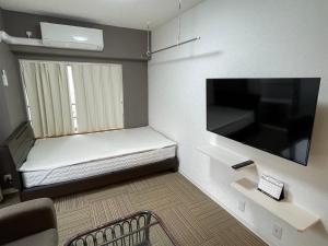 a small room with a bed and a flat screen tv at ROYAL YONEGAHAMA ｌ米が浜通 in Kusugaurachō