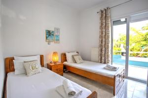a bedroom with two beds and a window with a pool at Villa Irene in Pefkohori