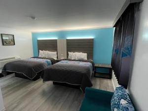 ein Schlafzimmer mit 2 Betten und einer blauen Wand in der Unterkunft Belmont Motel in Skowhegan