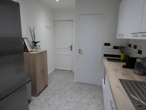 une cuisine avec des placards blancs et une porte blanche dans l'établissement LECOSY, au Boulou