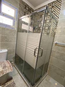La salle de bains est pourvue d'une douche avec une porte en verre. dans l'établissement A gorgeous furnished 3 BDs apt, à Ville du 6 Octobre