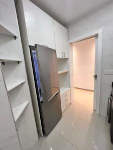 een keuken met een roestvrijstalen koelkast en witte kasten bij شقة في المضيق in M'diq