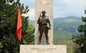 a statue of a soldier standing next to a red flag at Spring apartment in Permet in Përmet
