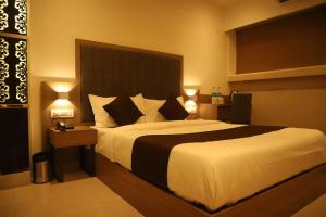 a bedroom with a large bed and two lamps at Hotel Sai Pritam in Mumbai