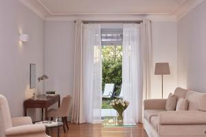 a living room with a couch and a desk and a window at Poseidonion Grand Hotel in Spetses