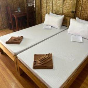 a large white bed with two brown napkins on it at Casa Gracia's Hotel and Restaurant in San Aquilino