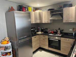 a kitchen with a stainless steel refrigerator and wooden cabinets at Appartement de luxe, front de mer Plage des nations in Salé