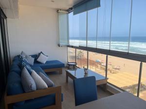 - un salon avec un canapé bleu et une vue sur la plage dans l'établissement Appartement de luxe, front de mer Plage des nations, à Sale