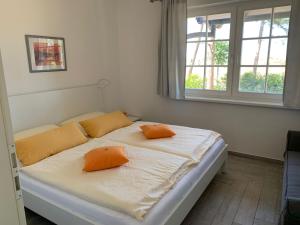 ein Schlafzimmer mit einem Bett mit zwei orangenen Kissen darauf in der Unterkunft Jan und Jana Ferienhaus in Ahrenshoop