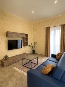 un soggiorno con un divano blu e una TV di Ta' Cikku Farmhouse a Xagħra Altre 11 foto
