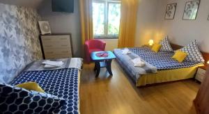 1 dormitorio con 2 camas y silla roja en Ranczo u Stefana, en Ustronie Morskie