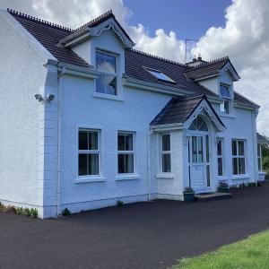 a white house with a black roof at Asdee House in Bushmills