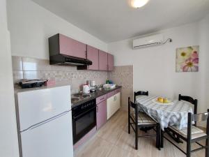 une cuisine avec des placards violets et une table avec une table dans l'établissement Apartmani Rahela, à Vodice