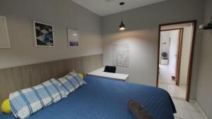 a bedroom with a blue bed and a bathroom at Lindo e novo ao lado da ETPC in Volta Redonda