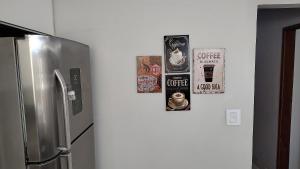 einen Kühlschrank in einer Küche mit Plakaten an der Wand in der Unterkunft Lindo e novo ao lado da ETPC in Volta Redonda