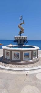 a large fountain with a cross on top of it at Captain John's Apartment in Diafani