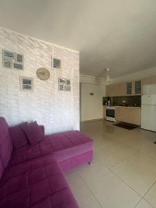 a purple couch in a living room with a kitchen at White Paradise in Paleo Tsifliki