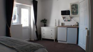 a bedroom with a bed and a kitchen and a window at Vernon Lodge Flat 2 in Bournemouth