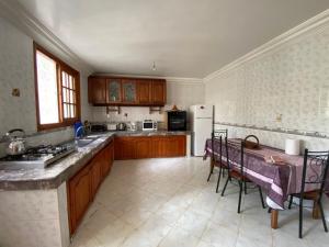 a kitchen with a table and a refrigerator at Rez-de-jardin à Mohammedia in Mohammedia