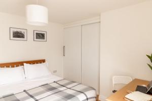a white bedroom with a bed and a desk at Amethyst Apartment in Oxford