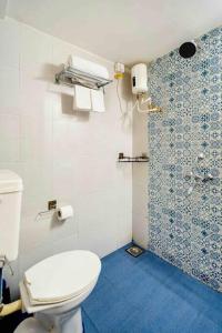 a bathroom with a white toilet and a shower at The Burrow in South Goa. in Dabolim
