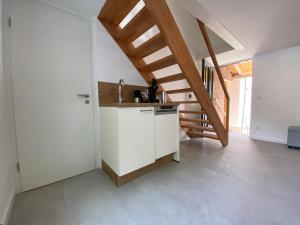 a kitchen with white cabinets and a wooden staircase at Ferienhaus Römer in Wirft