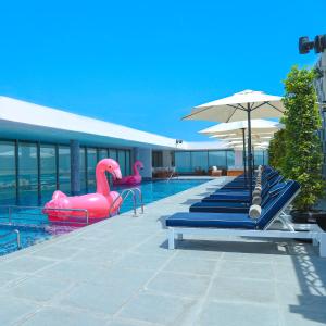 a swimming pool with inflatable swans and an umbrella at The Grove Hotel & Conference Centre Bahrain in Manama