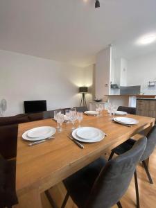 uma mesa de madeira com pratos e copos de vinho em Le CARNOT appartement avec 2 chambres séparés et parking privatif et securise em Arras