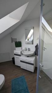 Baño blanco con lavabo y espejo en Helle Wohnung mit zwei Schlafzimmern en Eching