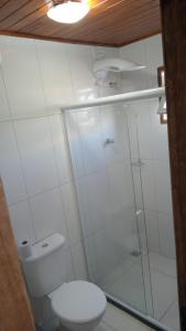 uma casa de banho com um WC e uma cabina de duche em vidro. em Pousada GPC em Macaé