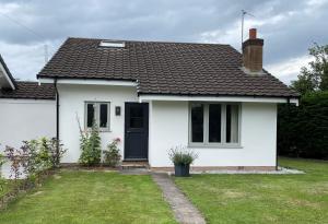 una casa blanca con una puerta negra y un patio en Fir Tree Cottage, en Chester