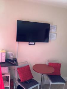 ein Zimmer mit einem Tisch und zwei Stühlen und einem Fernseher an der Wand in der Unterkunft Holm On The Lane in Birkenhead