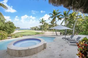 - une piscine avec des chaises et un parasol à côté de l'océan dans l'établissement 5BR Cap Cana Villa with Ocean & Golf Views, Chef, Maid, Butler, Pool, Jacuzzi, and Beach Club Access, à Punta Cana