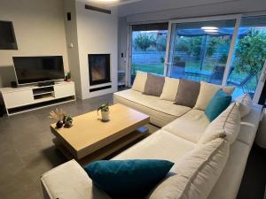 a living room with a white couch and a tv at Villa Joanne in Alexandroupoli