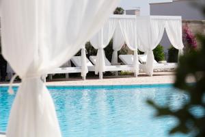 eine Reihe weißer Sonnenschirme neben einem Pool in der Unterkunft Borgo Mulino a Vento - Resort in Uggiano la Chiesa