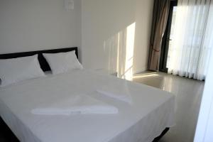 uma grande cama branca num quarto com uma janela em Mercan Suites Ilıca em Cesme