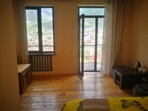 a bedroom with a large window and a wooden floor at Belas guesthouse in Stepantsminda