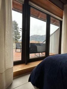 a bedroom with a window with a view of a deck at TERRAZAS DEL MASCARDI - LUXURY APARTMENT - INMEJORABLE UBICACION in San Martín de los Andes