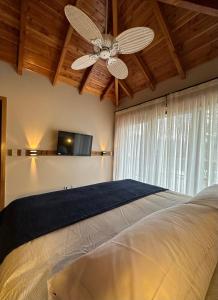 1 dormitorio con ventilador de techo y 1 cama en TERRAZAS DEL MASCARDI - LUXURY APARTMENT - INMEJORABLE UBICACION en San Martín de los Andes
