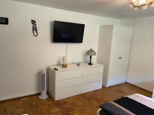 ein Schlafzimmer mit einer weißen Kommode und einem TV an der Wand in der Unterkunft Cal-ifornia Home 2 in Nürnberg