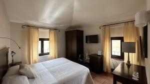 a bedroom with a white bed and two windows at Hotel Palazzo Piccolomini in Orvieto