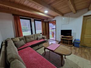 ein Wohnzimmer mit einem Sofa und einem Tisch in der Unterkunft Bungalovi Menzil in Zavidovići