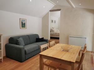 ein Wohnzimmer mit einem Sofa und einem Tisch in der Unterkunft Gîte la Borie du bois Sarlat in Saint-André-dʼAllas