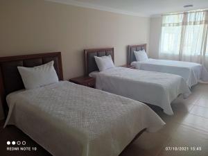 2 camas en una habitación de hotel con sábanas blancas en HOTEL SHANGHAI CITY, en Ibarra