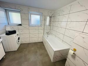 a bathroom with a tub and a washing machine at Apartamenty Bałtyckie in Sopot