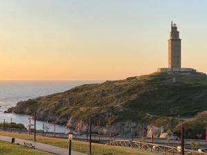 a lighthouse sitting on top of a hill next to the ocean at Blue Ocean Apartment in A Coruña