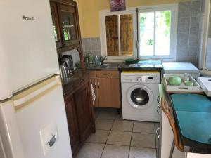 a kitchen with a washing machine and a sink at chambre et salle de bain privé s'ouvrant sur terrasse, jardin et cuisine d'été in Quillan